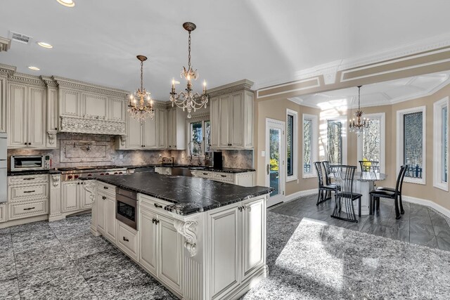 kitchen with a center island, stainless steel appliances, backsplash, cream cabinetry, and ornamental molding