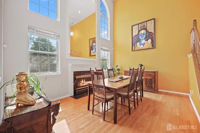 7 Cornell Dr, East Brunswick, NJ 08816 - dining space featuring a towering ceiling, baseboards, hardwood / wood-style flooring, and a fireplace with flush hearth