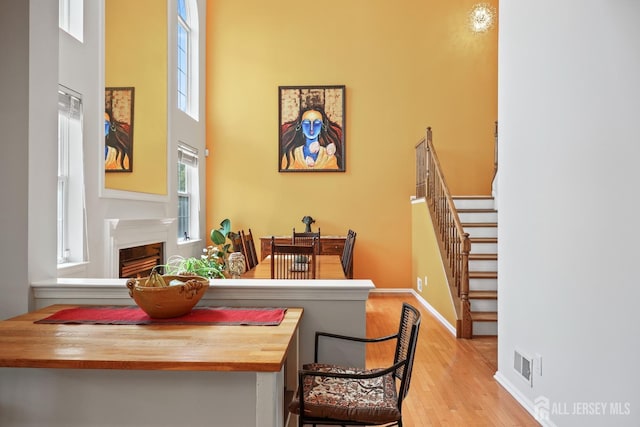 7 Cornell Dr, East Brunswick, NJ 08816 - dining room with wood finished floors, a fireplace, stairs, a high ceiling, and baseboards