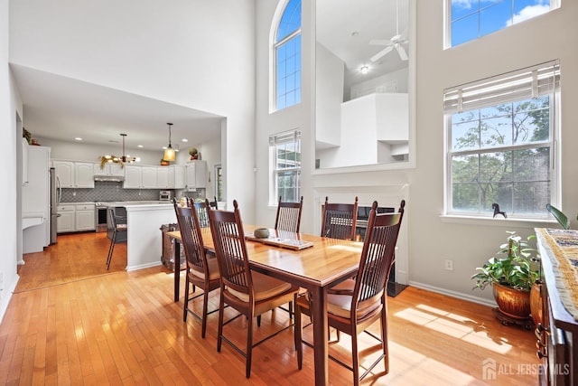 7 Cornell Dr, East Brunswick, NJ 08816 - dining room featuring light wood-style flooring, a towering ceiling, a ceiling fan, baseboards, and a chandelier