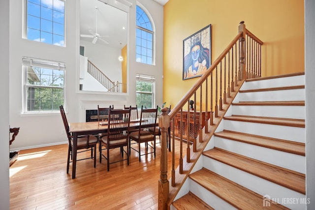 7 Cornell Dr, East Brunswick, NJ 08816 - dining area featuring ceiling fan, wood-type flooring, stairs, a towering ceiling, and baseboards