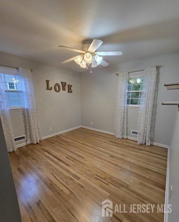 unfurnished room with baseboards, wood finished floors, and a ceiling fan