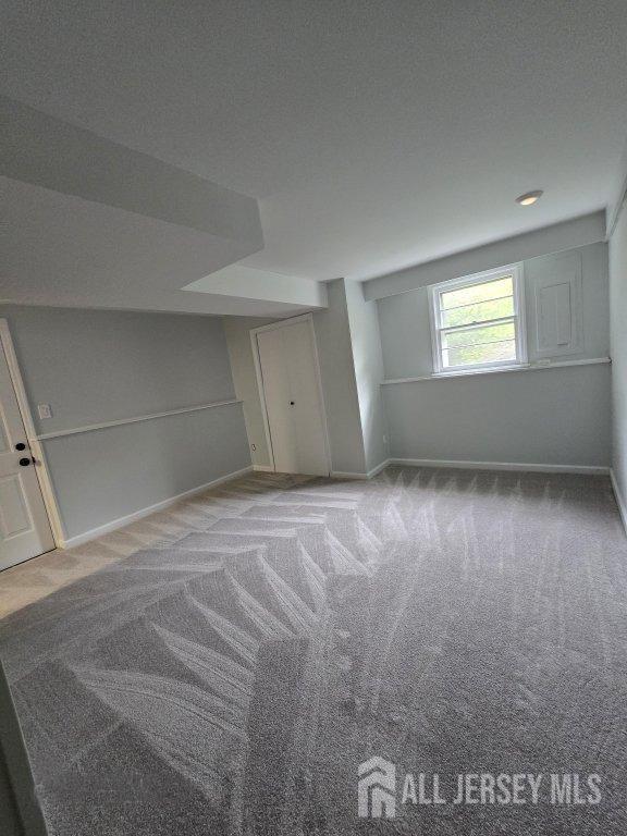 below grade area featuring a textured ceiling, baseboards, and carpet