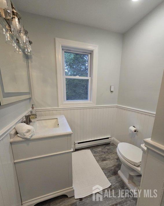 bathroom with hardwood / wood-style floors, vanity, a baseboard radiator, and toilet