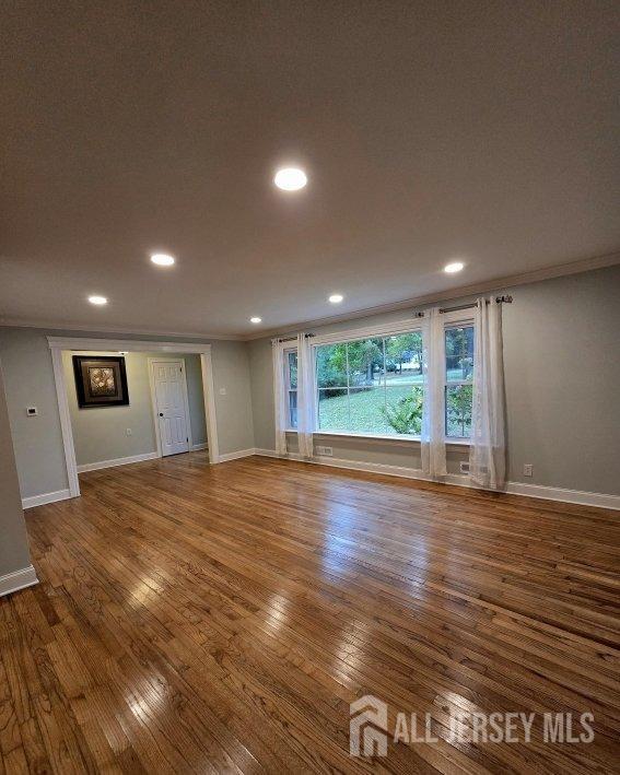 empty room featuring hardwood / wood-style floors, recessed lighting, baseboards, and ornamental molding