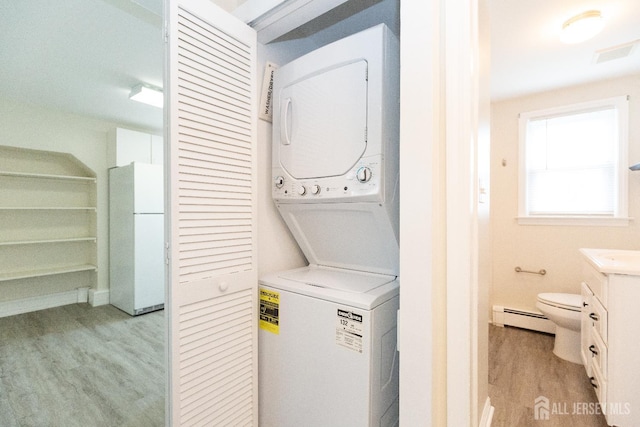 200 Plainfield Rd, Edison, NJ 08820 - laundry room featuring estacked washer and dryer, light wood-type flooring, and a baseboard heating unit