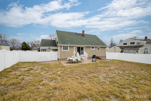 back of house with entry steps, a fenced backyard, a yard, a chimney, and a patio area