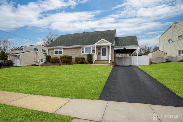 view of front facade featuring an attached carport, a shingled roof, fence, aphalt driveway, and a front yard