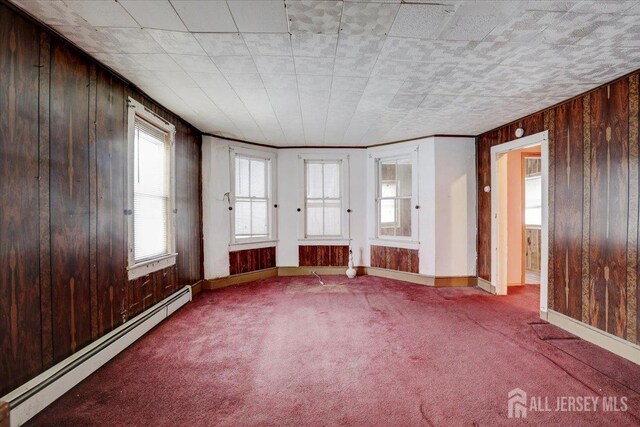 interior space featuring a baseboard radiator, wood walls, and carpet flooring