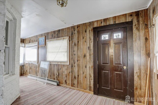 carpeted entrance foyer featuring wooden walls and a baseboard heating unit