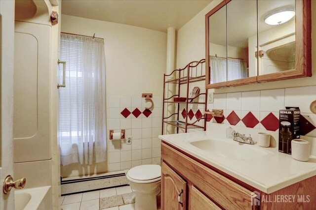 bathroom featuring tile patterned flooring, tile walls, a baseboard radiator, backsplash, and vanity