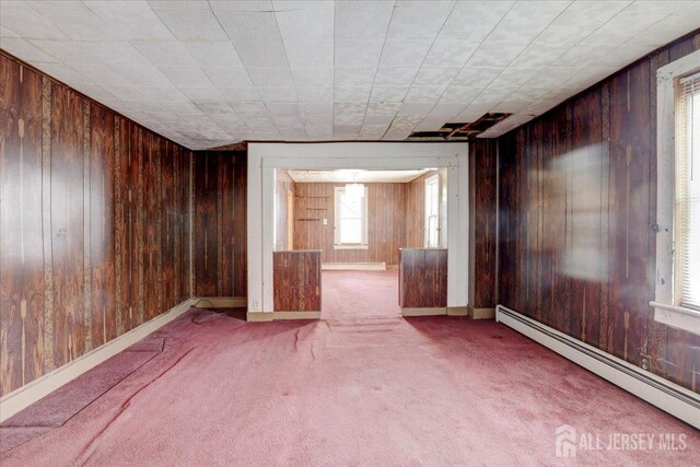 spare room with wooden walls, carpet floors, and baseboard heating