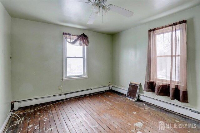 spare room with baseboard heating, hardwood / wood-style floors, and a wealth of natural light