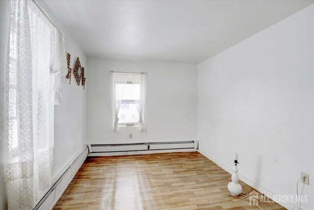 spare room with a baseboard heating unit and light hardwood / wood-style flooring