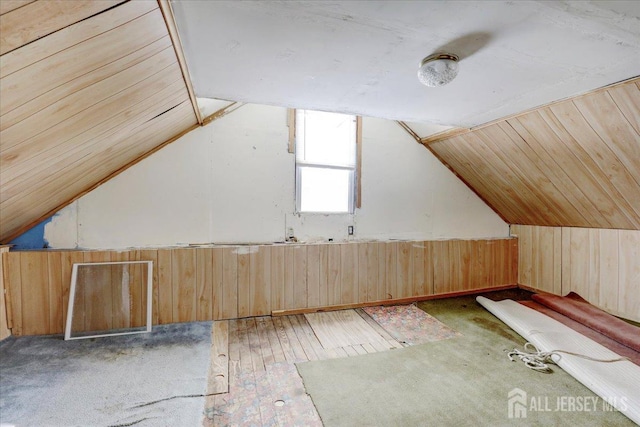 additional living space featuring lofted ceiling, wood-type flooring, and wood walls