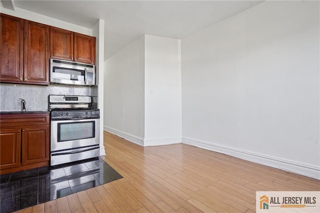 57 Corbin Ave Unit 24, Jersey City, NJ 07306 - kitchen featuring appliances with stainless steel finishes, wood finished floors, backsplash, and dark countertops
