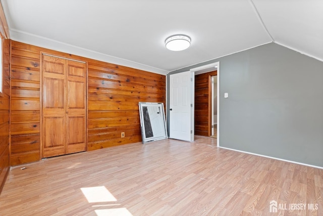 unfurnished bedroom featuring lofted ceiling and light wood-type flooring