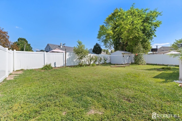 view of yard featuring a fenced backyard, an outdoor structure, and a storage shed