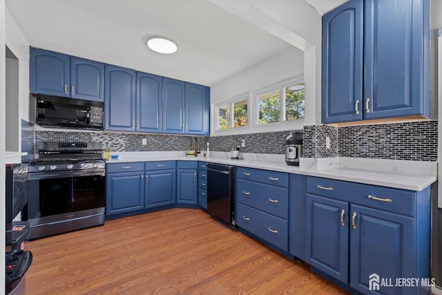 kitchen with blue cabinets, backsplash, black appliances, and wood finished floors