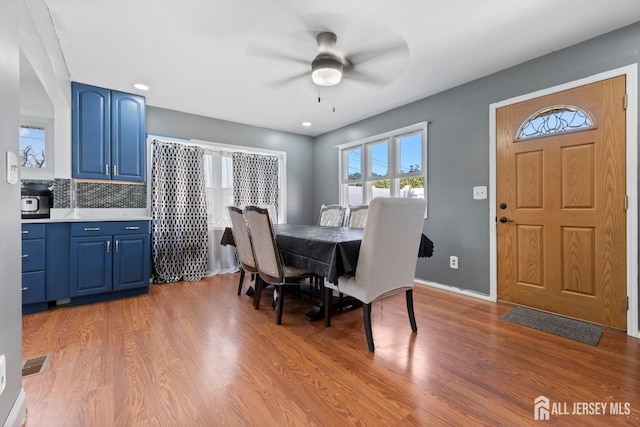 dining room featuring baseboards, ceiling fan, visible vents, and wood finished floors