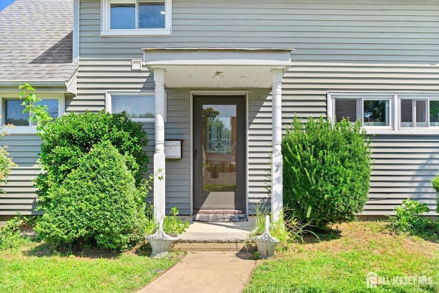 doorway to property with a shingled roof