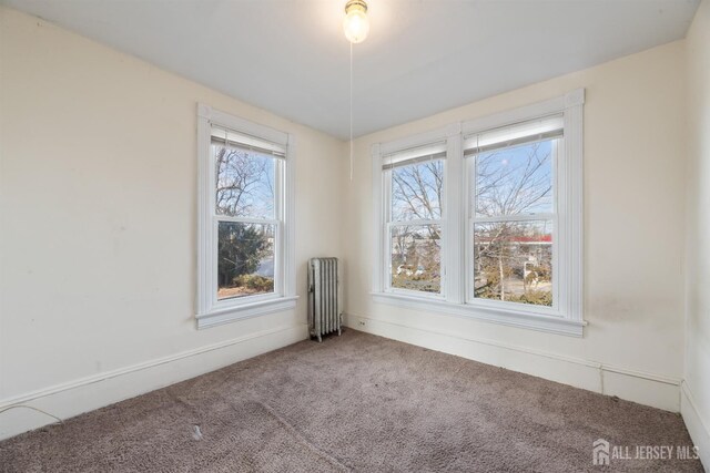 unfurnished room with radiator and carpet flooring