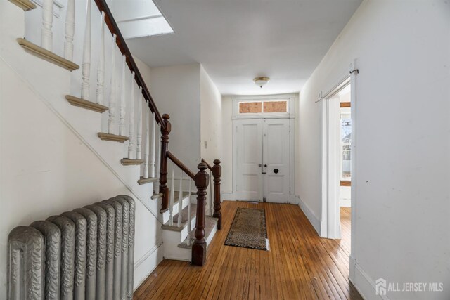 entryway with hardwood / wood-style floors and radiator heating unit