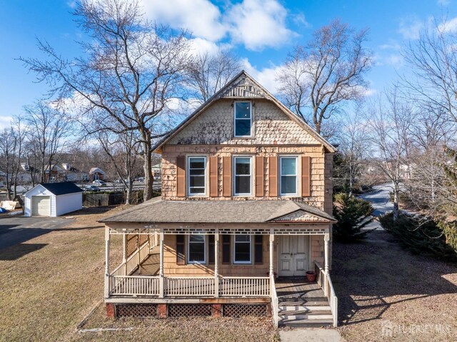 view of front of house featuring an outbuilding, a front yard, covered porch, and a garage