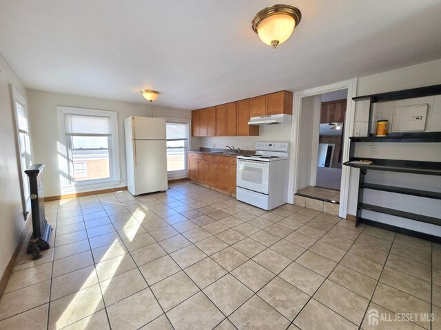 kitchen with light tile patterned floors, white appliances, and sink