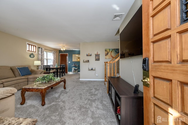 living room with visible vents, baseboards, carpet, stairs, and a ceiling fan