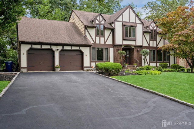 tudor-style house featuring a garage and a front lawn