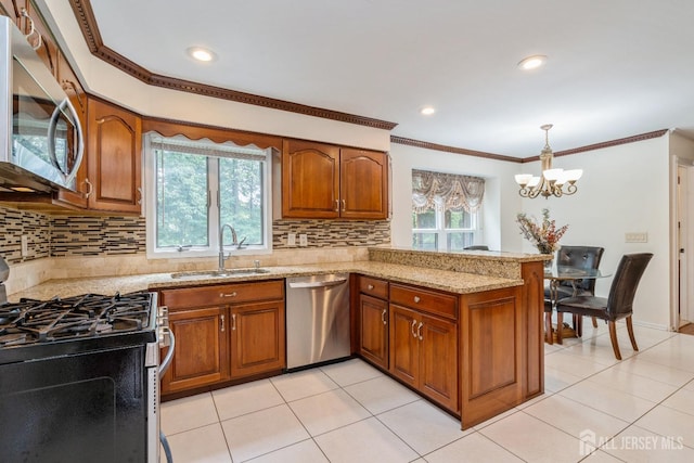 kitchen featuring sink, hanging light fixtures, stainless steel appliances, light stone counters, and kitchen peninsula