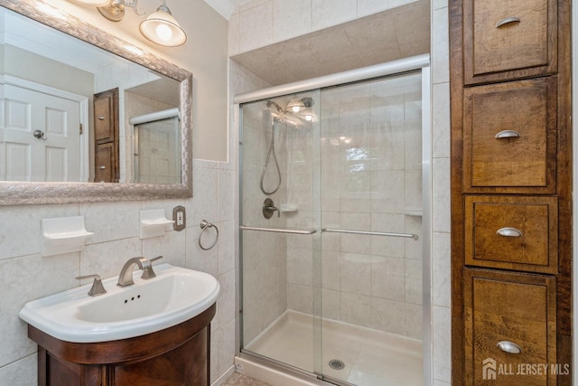 bathroom with vanity, a shower with shower door, and tile walls