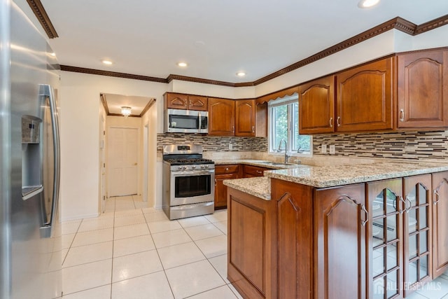 kitchen featuring appliances with stainless steel finishes, sink, backsplash, light stone counters, and kitchen peninsula