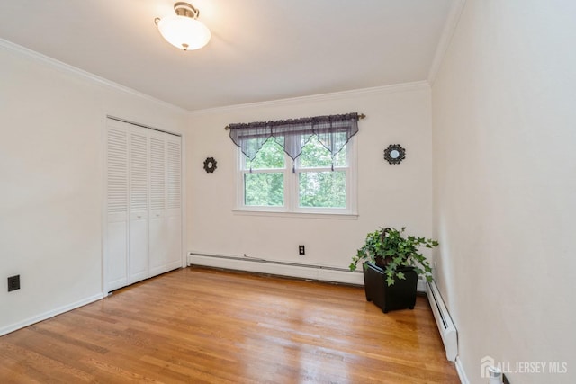 unfurnished bedroom featuring baseboard heating, crown molding, light hardwood / wood-style floors, and a closet