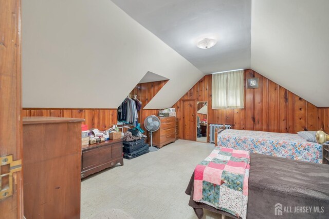 carpeted bedroom featuring vaulted ceiling and wooden walls