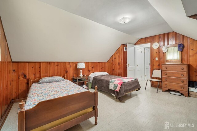 bedroom with lofted ceiling and wood walls