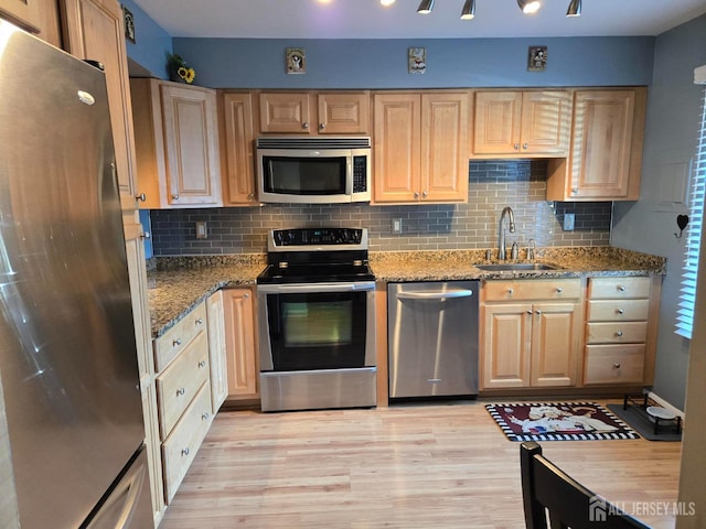 kitchen with light stone counters, stainless steel appliances, light hardwood / wood-style flooring, and sink