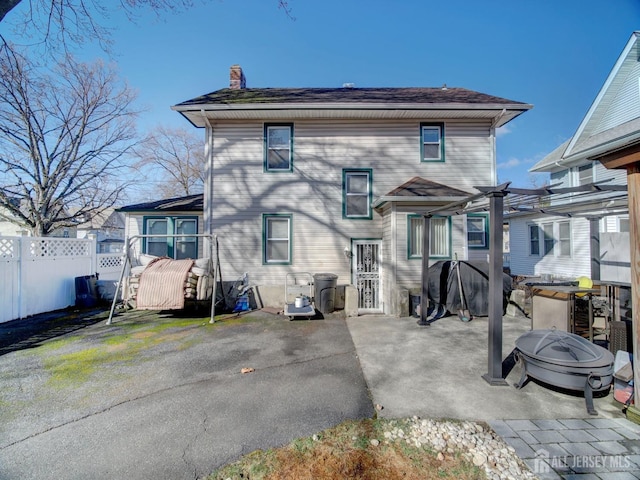 rear view of house featuring fence, a patio, and a chimney