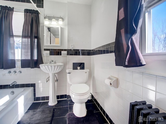full bathroom with tile walls, toilet, tile patterned flooring, and a healthy amount of sunlight