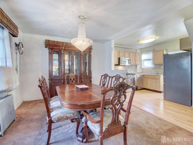 dining area with an inviting chandelier, light carpet, radiator, and baseboards