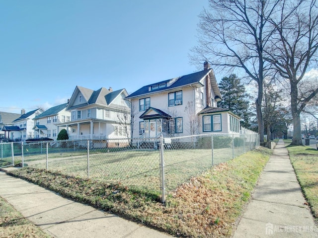 victorian-style house featuring a chimney, a residential view, a front lawn, and fence private yard