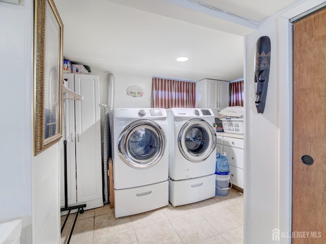 laundry room featuring separate washer and dryer, cabinet space, and light tile patterned floors