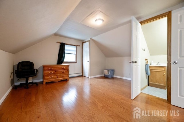 bonus room with a baseboard radiator, light wood-type flooring, a sink, lofted ceiling, and baseboards