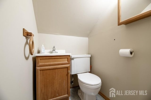 bathroom with lofted ceiling, toilet, and vanity