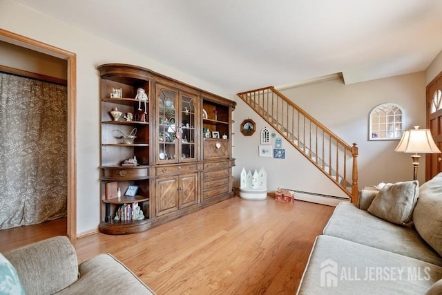 living area with a baseboard radiator, stairs, and wood finished floors