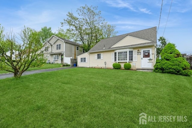 view of front of home with a front yard and a shingled roof