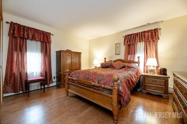 bedroom with wood finished floors and a baseboard radiator
