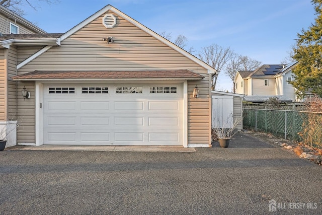 garage with aphalt driveway and fence