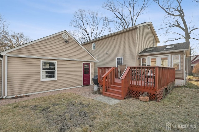 rear view of property featuring a wooden deck and a lawn